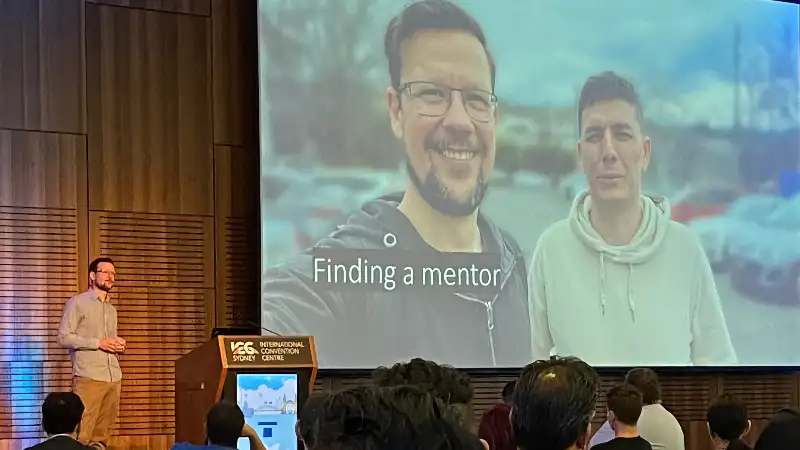 Philip is on stage beside a large slide titled "Finding a mentor"